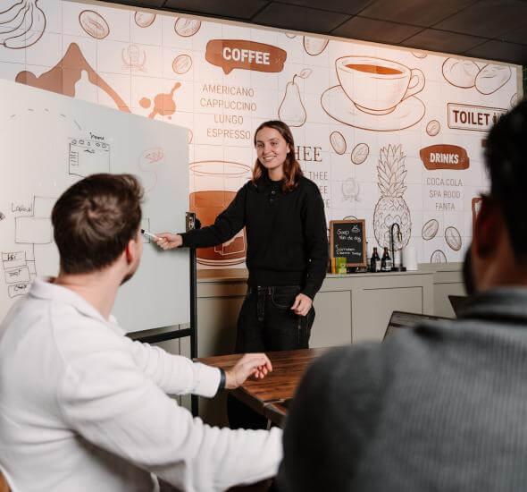 Meeting binnen het Atom team waarbij iets wordt uitgelegd op een whiteboard