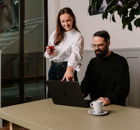 Medewerkers van Atom die samen achter hun laptop zitten