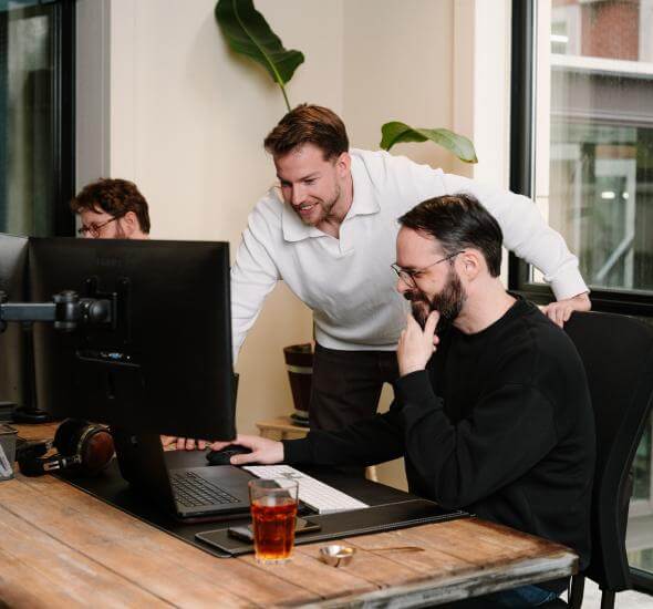 Medewerkers van Atom Rotterdam samen achter een computer in overleg