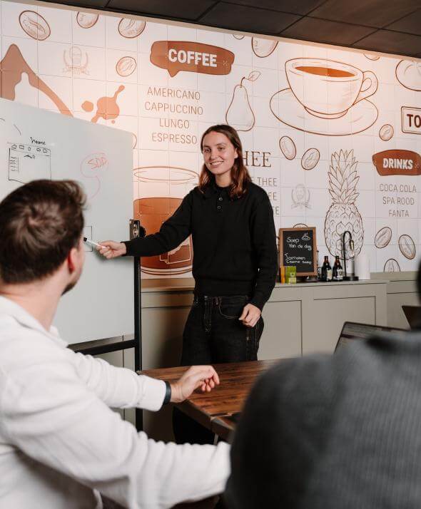 Meeting binnen het Atom team waarbij iets wordt uitgelegd op een whiteboard