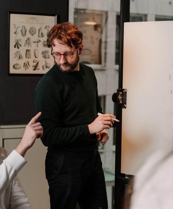 Een medewerker van Atom vraagt iets tijdens een presentatie aan een andere medewerker